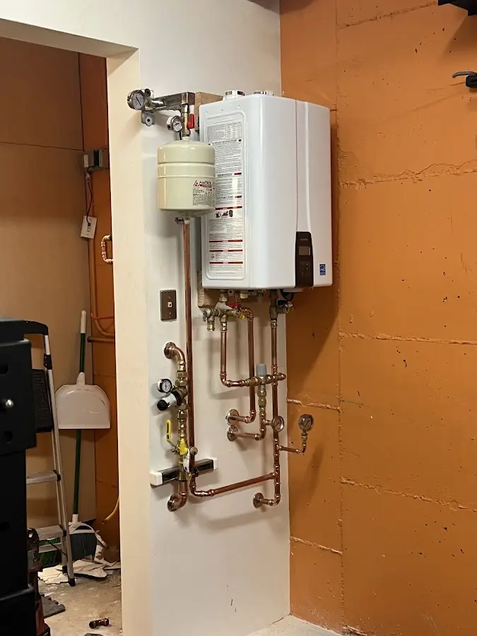 Plumbing technician inspecting water heater connections in Geddes
